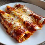 Close-up of three rolled cheese enchiladas covered in red sauce and melted white and yellow cheese.