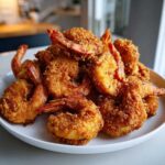 A generous pile of perfectly golden and crispy fried shrimp served on a white plate.