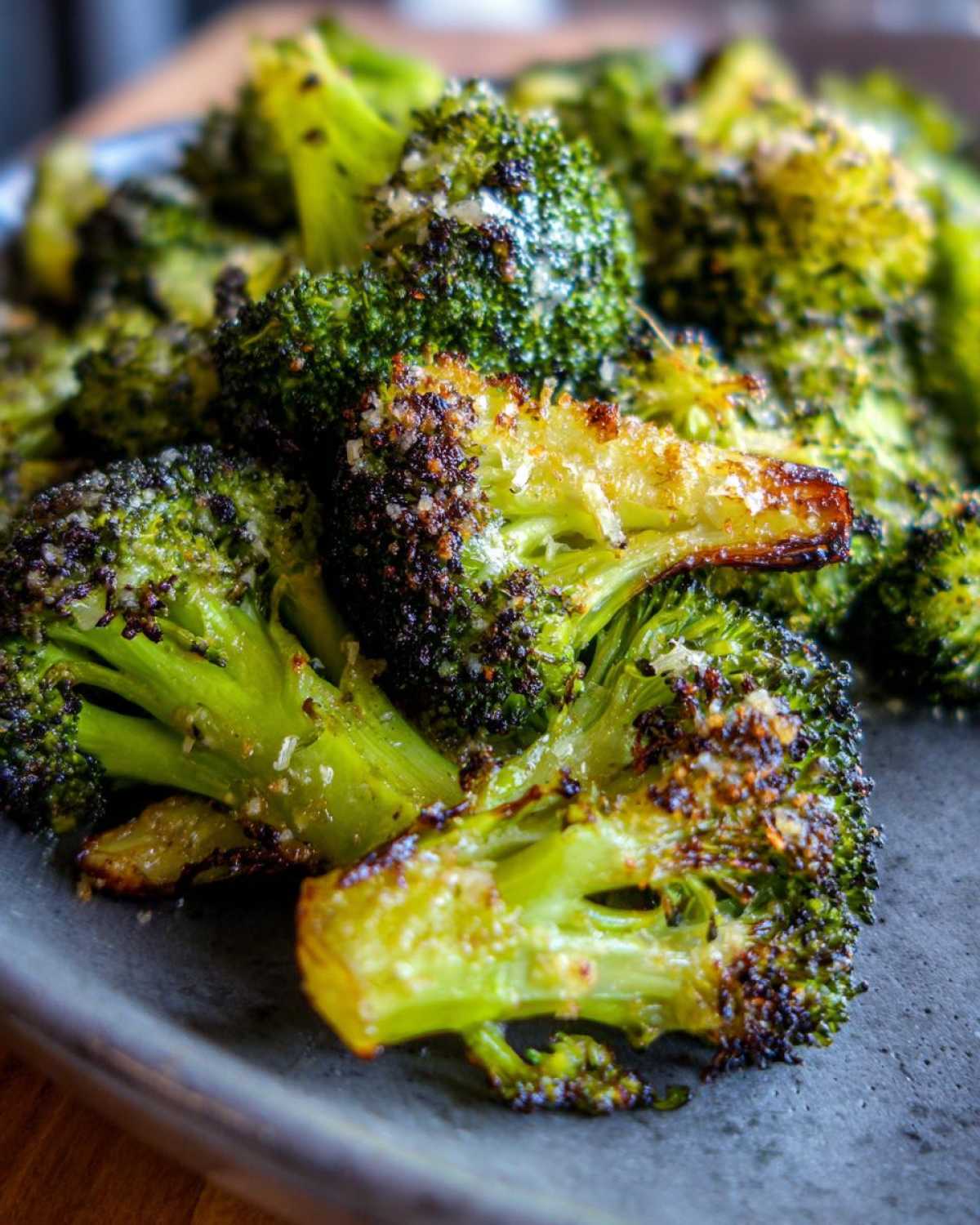 Close-up of bright green, caramelized roasted broccoli florets topped with grated Parmesan cheese.
