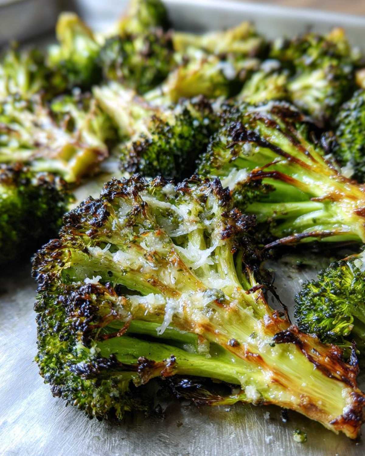 Close-up of perfectly roasted broccoli florets with crispy, charred edges and melted Parmesan cheese.