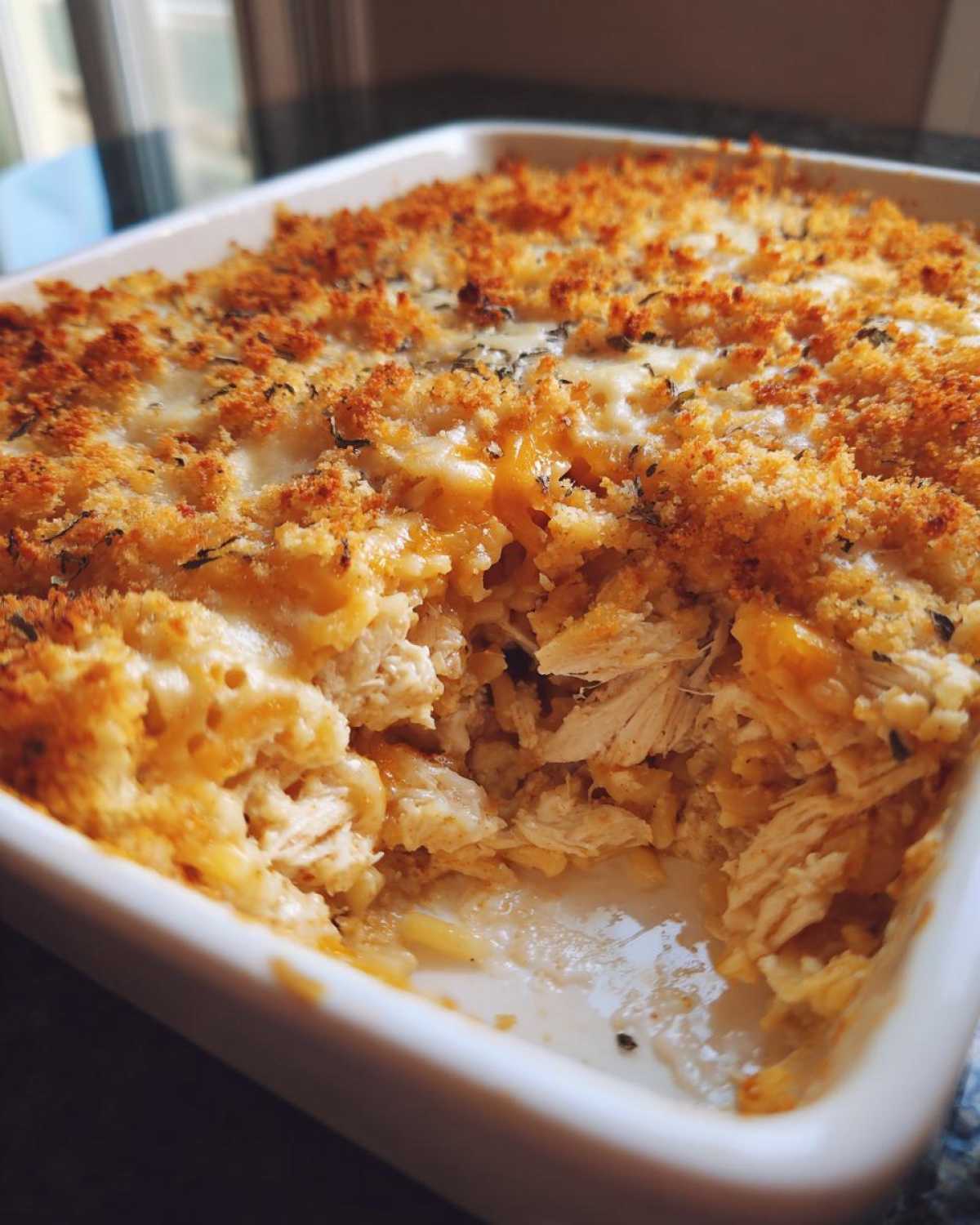 Close-up of a portion of baked Chicken Spaghetti showing shredded chicken, creamy sauce, and a golden, crunchy breadcrumb topping.