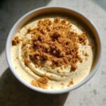 Overhead view of creamy Banana Cream Pie Blended Chia pudding topped with brown sugar crumble in a white bowl.
