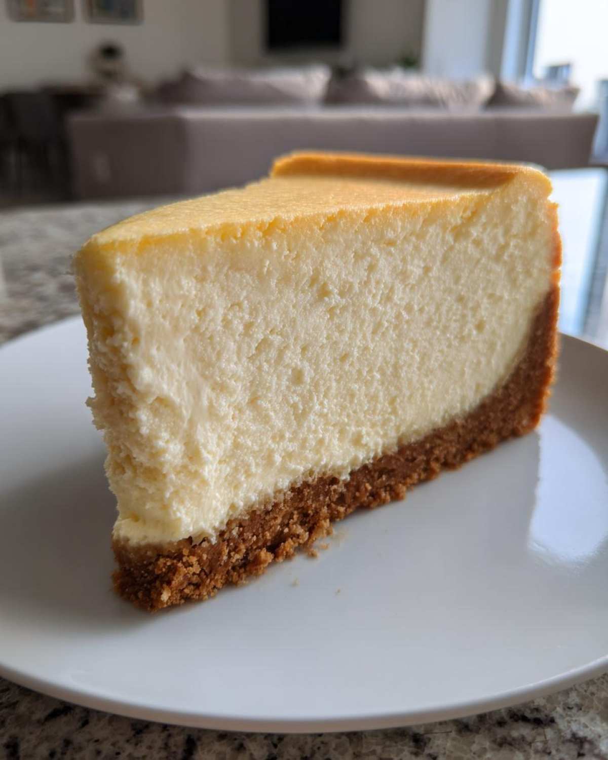A thick, creamy slice of classic cheesecake with a graham cracker crust, ready to eat.