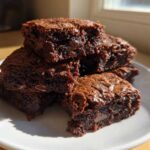 A stack of irresistibly chewy brown butter brownies with visible chocolate chips on a white plate.