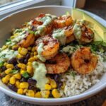 Close-up of a Chipotle Lime Shrimp Bowl featuring grilled shrimp, corn, black beans, rice, and a creamy green sauce.
