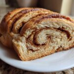 A close-up of a thick slice of homemade Cinnamon Swirl Bread showing the beautiful brown sugar and cinnamon spiral filling.