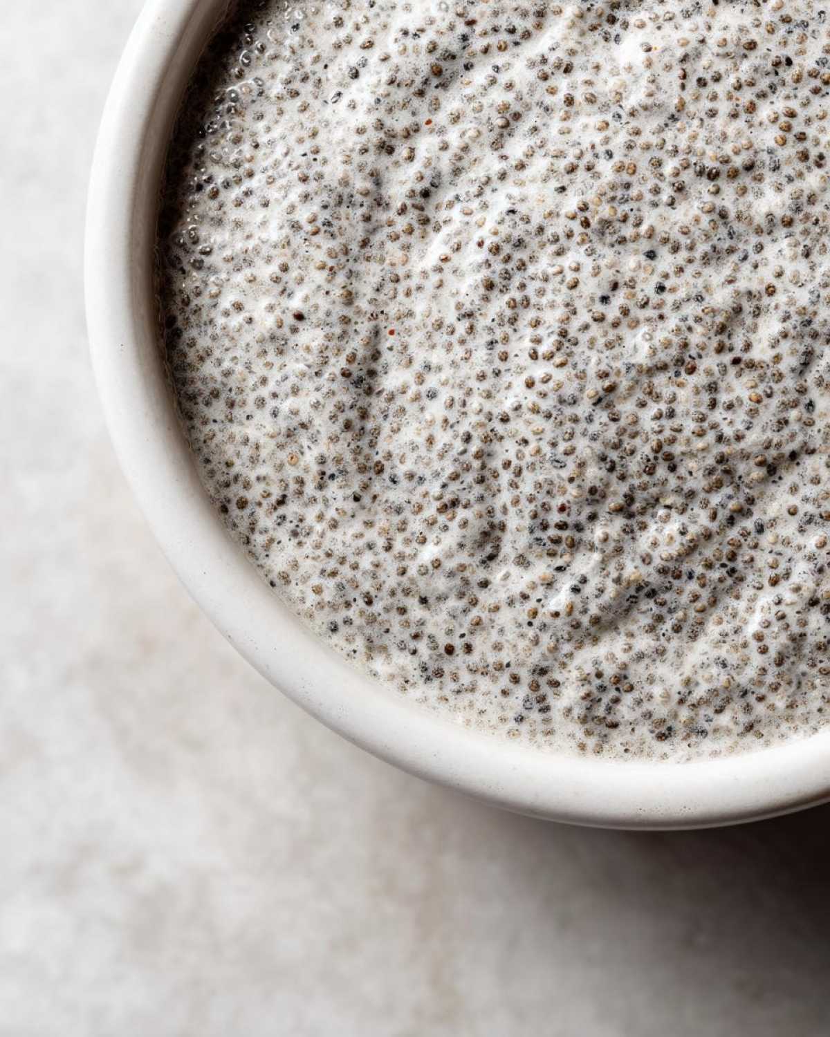 A close-up, overhead view showing the thick, creamy texture of coconut chia pudding in a white bowl.