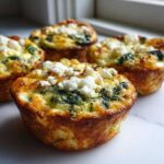 Close-up of baked Cottage Cheese Egg Cups With Spinach & Feta, topped with crumbled white cheese.
