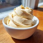 A perfectly swirled serving of creamy banana ice cream in a small white bowl.
