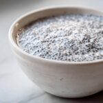 Close-up of thick, creamy coconut chia pudding showing hydrated chia seeds in white liquid.