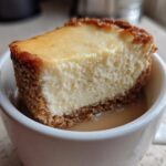 Close-up of a slice of Decadent Cheesecake Mug Recipe resting in a white mug with coffee.