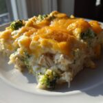A close-up serving of creamy Dump and Bake Chicken Casserole topped with melted cheddar cheese and broccoli florets.