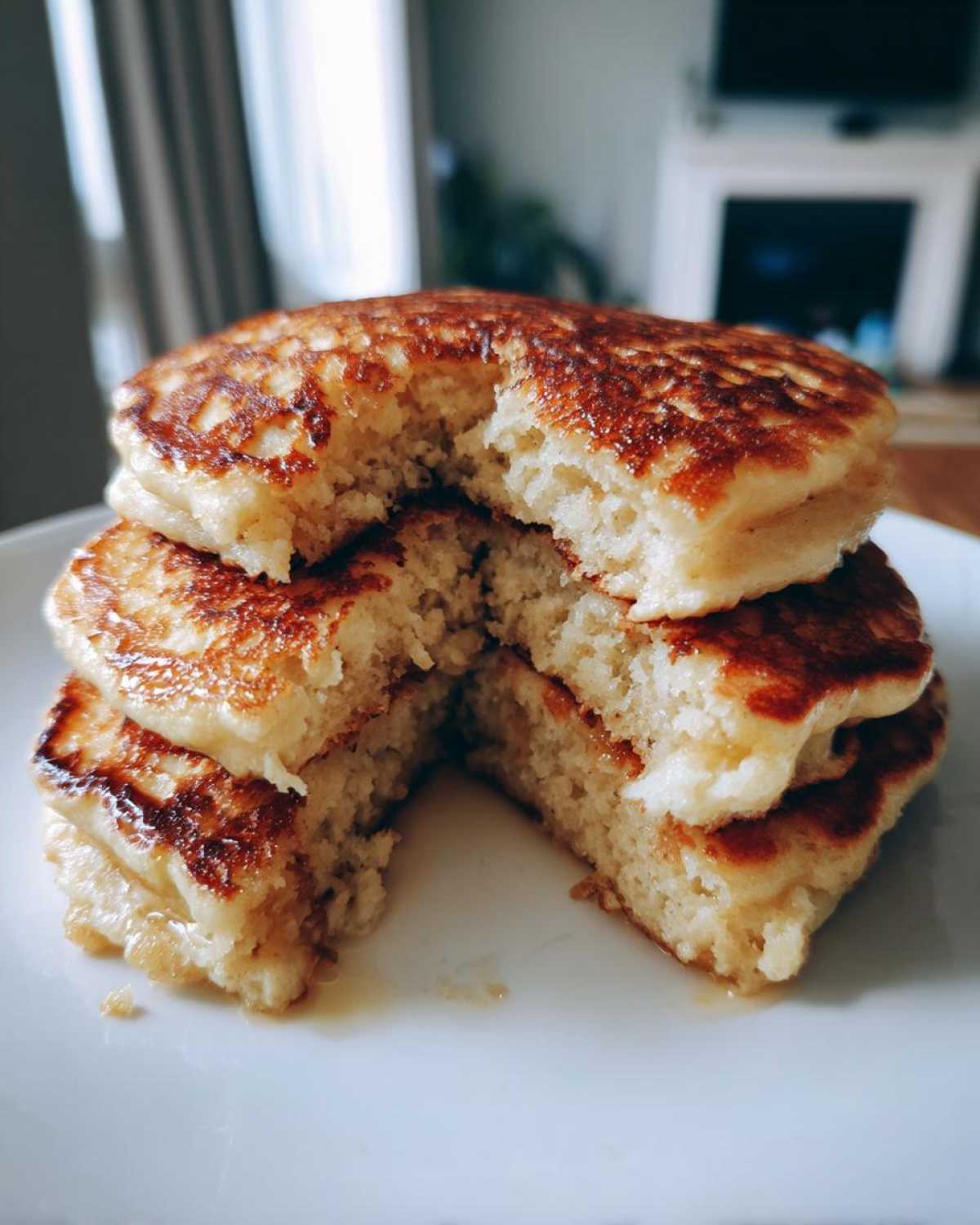 Close-up of a stack of fluffy banana pancakes cut in half showing the moist interior and golden-brown edges.