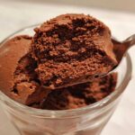 A spoonful of light and airy chocolate mousse being lifted from a glass serving.