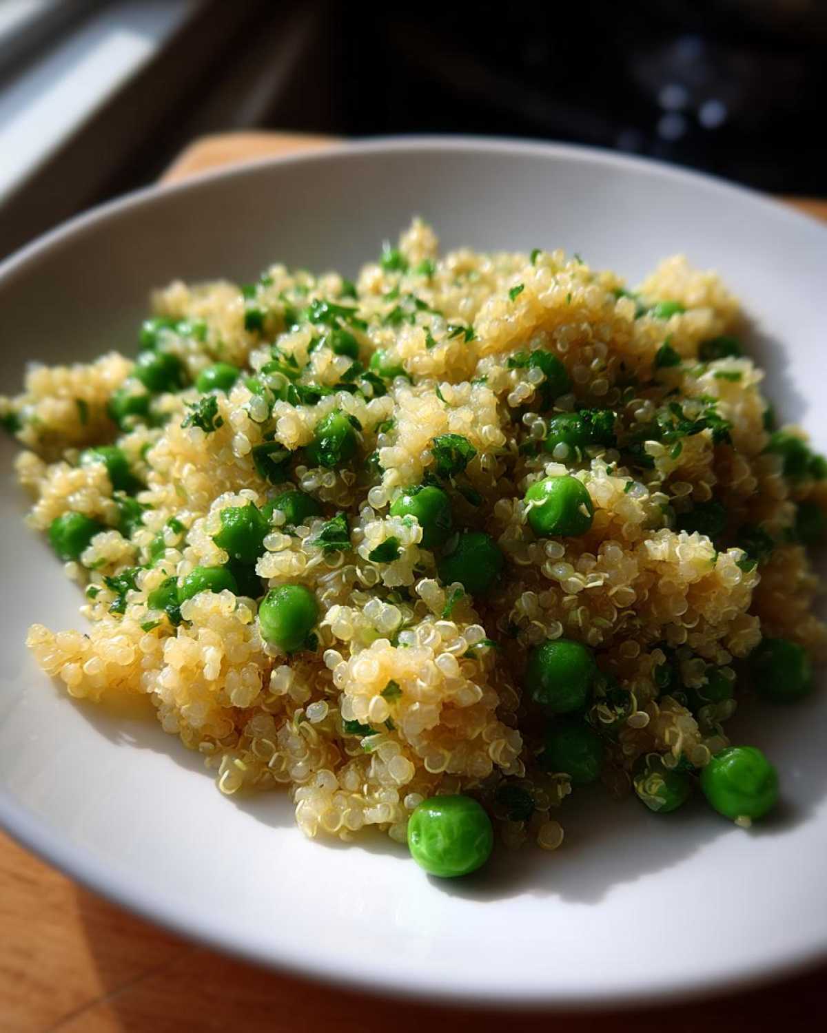 A close-up of Garlic Butter Quinoa Green Peas mixed with chopped parsley, served in a white bowl.