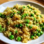 A close-up of fluffy Garlic Butter Quinoa Green Peas mixed together on a white plate.