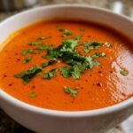 Close-up of rich, orange-red Garlic Tikka Masala Sauce topped with fresh chopped cilantro in a white bowl.