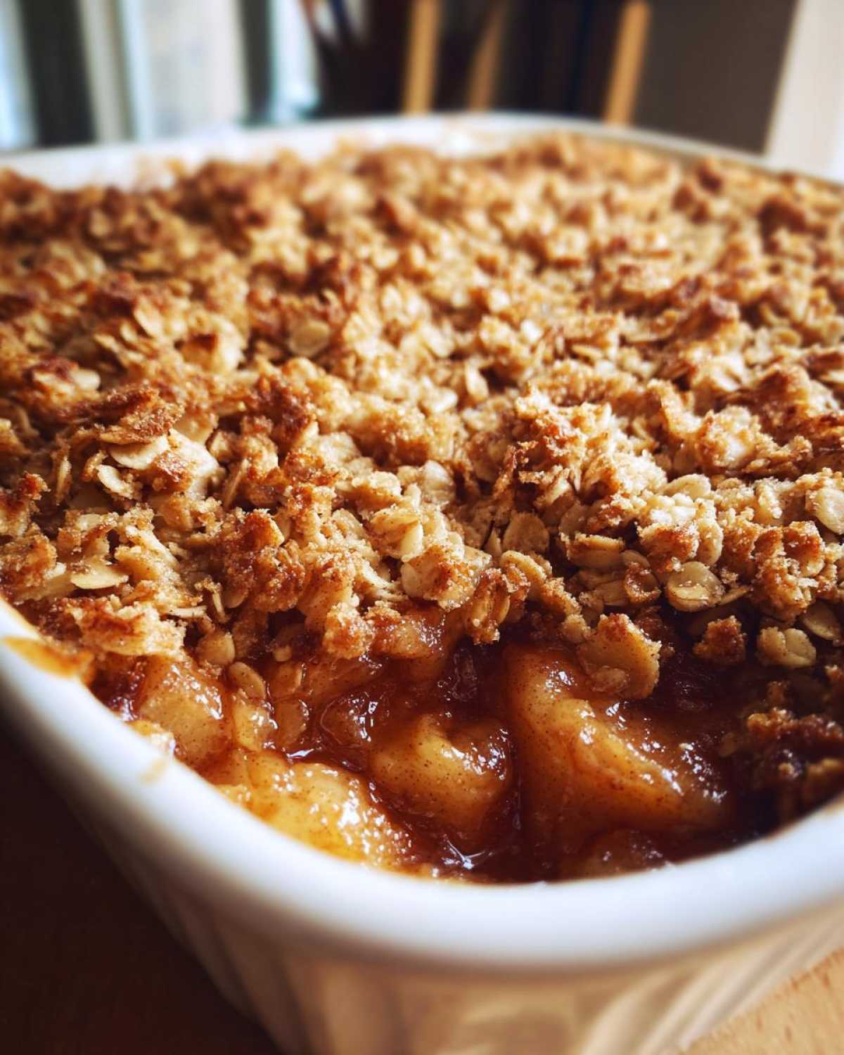 Close-up of a golden brown, baked apple crisp recipe showing bubbling spiced apples beneath a crunchy oat topping.