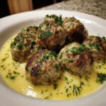 Close-up of browned Greek Meatballs in Lemon Sauce, garnished generously with fresh dill.