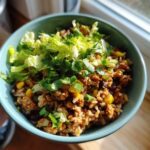 Close-up of a serving of Ground Turkey Rice Bowls mixed with corn and beans, topped with shredded lettuce and cilantro.