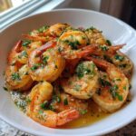 Close-up of succulent Hawaiian Garlic Shrimp coated in buttery garlic sauce and fresh parsley in a white bowl.