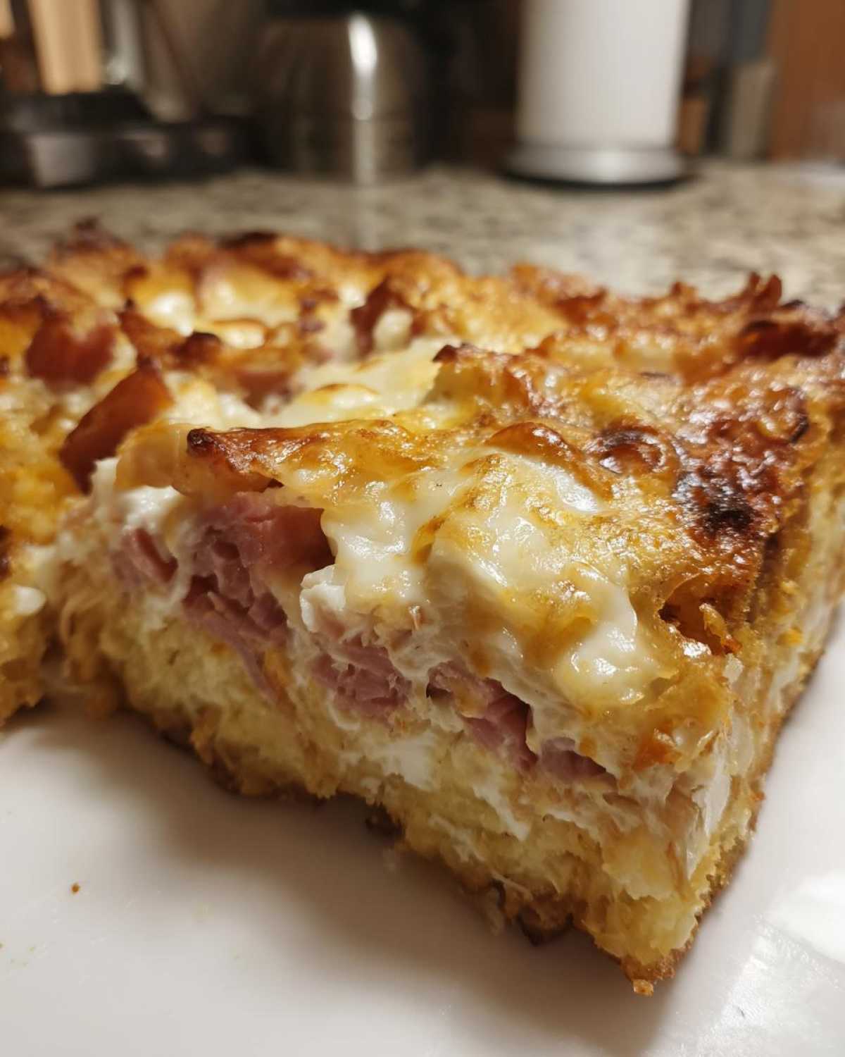 Close-up of a thick slice of homemade Reuben bake showing layers of bread, ham, and melted cheese topping.