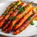 Close-up of glossy, caramelized honey garlic roasted carrots garnished with fresh chopped parsley.