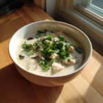 Close-up of a creamy bowl of Irresistible Thai Chicken Soup topped generously with fresh cilantro.