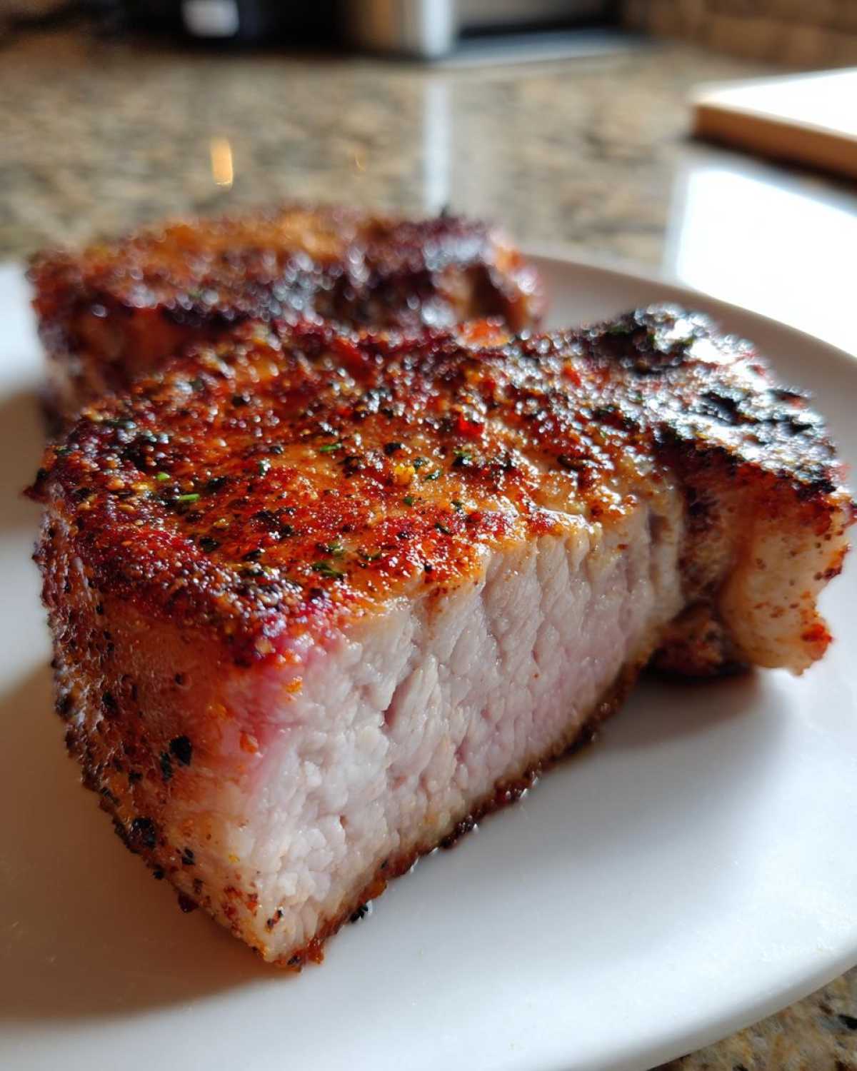 Close-up of a thick, juicy air fryer pork chop showing a perfectly cooked pink interior and seasoned crust.