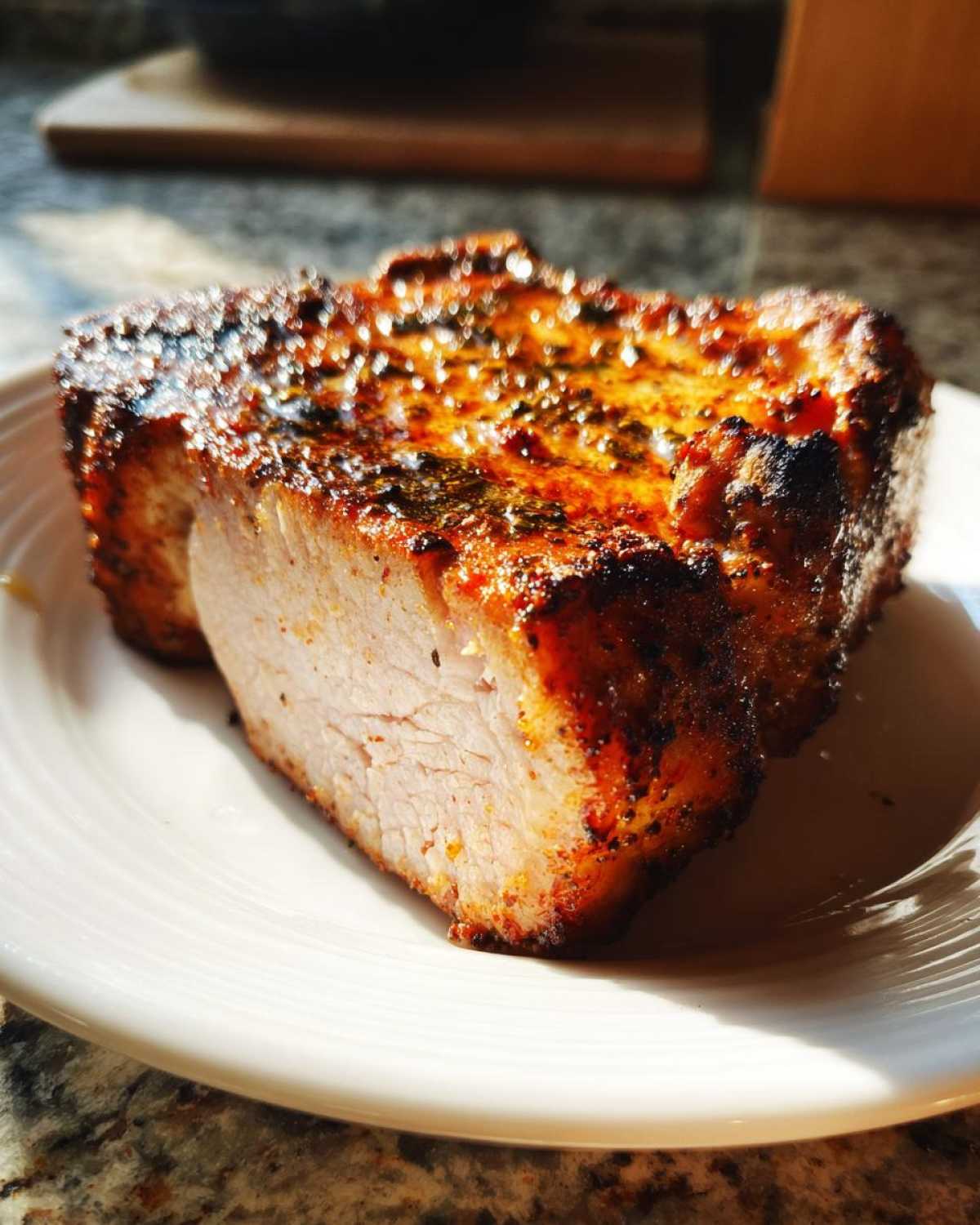 Close-up of a thick, perfectly cooked air fryer pork chop, showing a juicy interior and caramelized, seasoned crust.