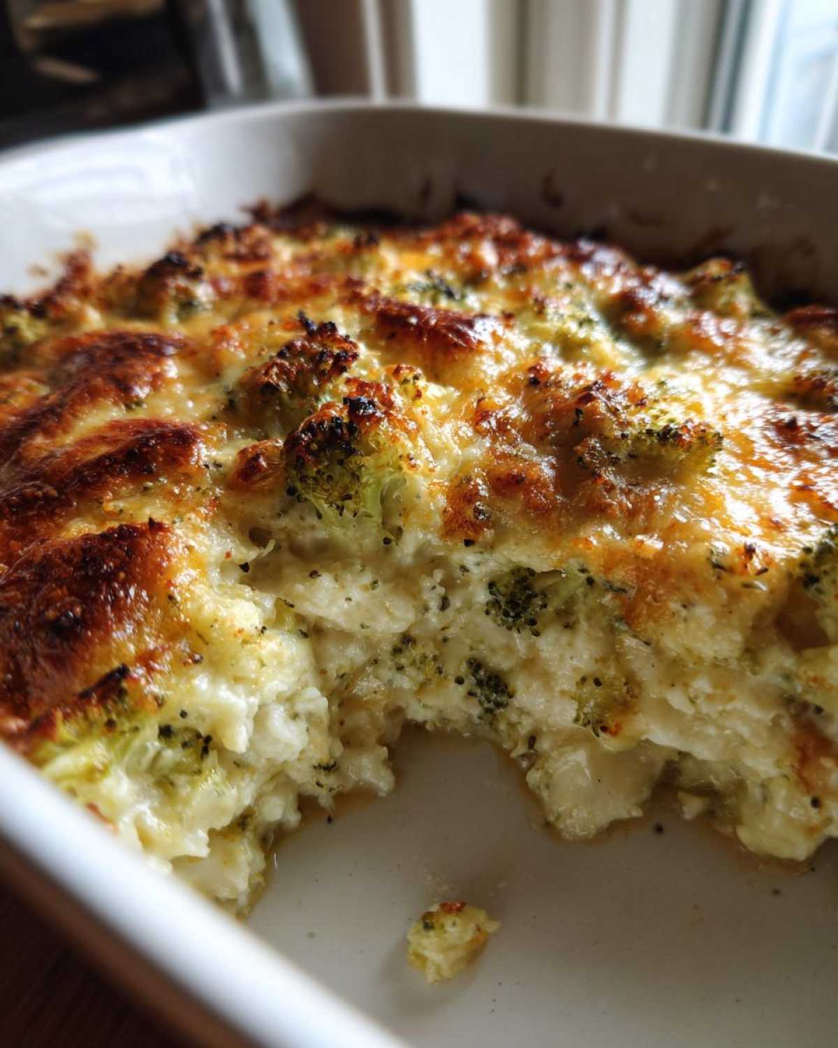 Close-up of a bubbly, baked Keto Broccoli Cauliflower Au Gratin with a golden-brown cheese crust.