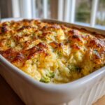 Close-up of a bubbling Keto Broccoli Cauliflower Au Gratin baked in a white casserole dish with a golden-brown cheese crust.