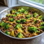 Close-up of Keto Hamburger Broccoli Skillet cooked in a pan, topped with melted cheddar cheese.