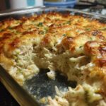 A glass baking dish filled with a creamy, cheesy Low Carb Chicken Casserole, showing a scoop removed to reveal shredded chicken and broccoli.