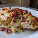 A close-up of Malibu Chicken Cheesy Bacon Chicken topped with melted cheese and crispy bacon bits.