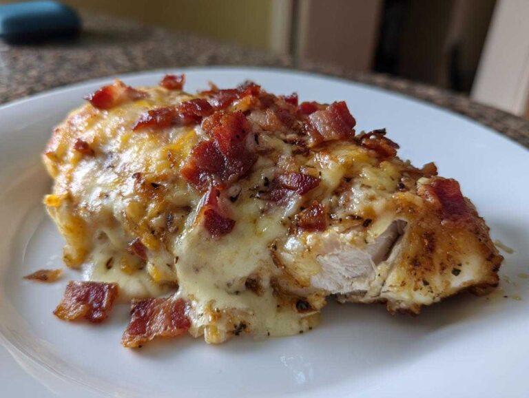 A close-up of Malibu Chicken Cheesy Bacon Chicken topped with melted cheese and crispy bacon bits.
