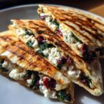 Close-up of three grilled Mediterranean Quesadillas wedges filled with white feta cheese, spinach, and olives.