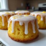 Four moist Mini Lemon Cakes Recipe bites topped with dripping white lemon glaze and zest.