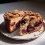 Two slices of moist plum cake featuring baked plums and a thick brown sugar crumb topping.