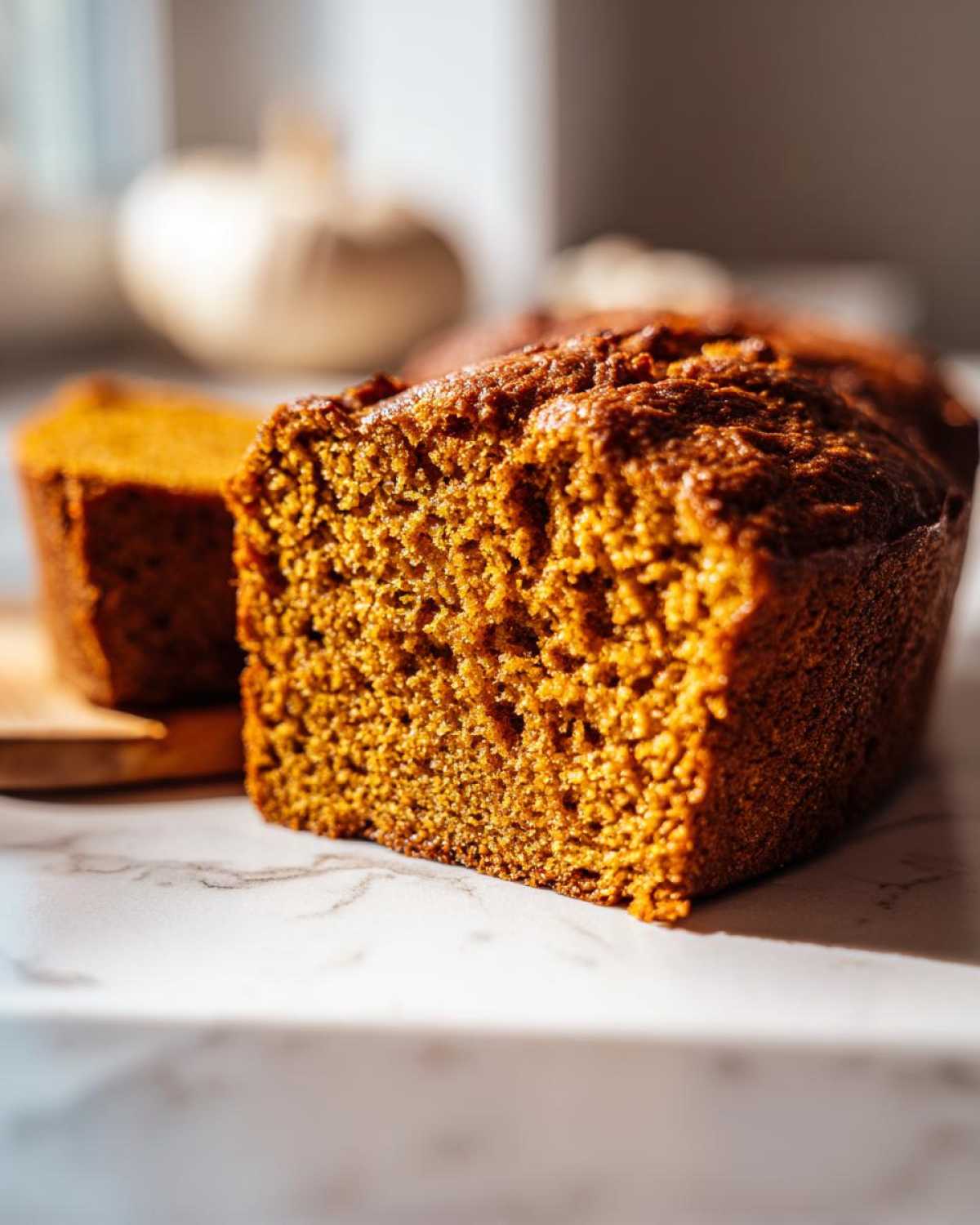 Close-up of a freshly baked, moist pumpkin bread loaf showing its rich, orange crumb texture.
