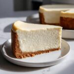 A perfect slice of Nobake Cheesecake Silky Sets Perfectly showing a thick graham cracker crust and creamy white filling.