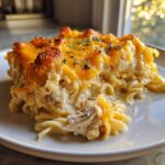 A close-up serving of creamy One Pan Ground Turkey Casserole topped with melted, browned cheddar cheese and parsley.