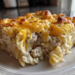 A close-up slice of creamy One Pan Ground Turkey Casserole topped with melted, browned cheddar cheese.