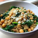 A close-up of a white bowl filled with the One Pot Chickpea Quinoa Recipe, featuring quinoa, chickpeas, spinach, and feta cheese.