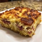 Close-up of a square slice of homemade reuben bake with a golden-brown, cheesy crust and visible layers of meat and creamy filling.