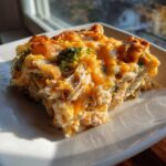 A close-up of a serving of Dump and Bake Chicken Casserole with shredded chicken, broccoli, and melted cheddar cheese.