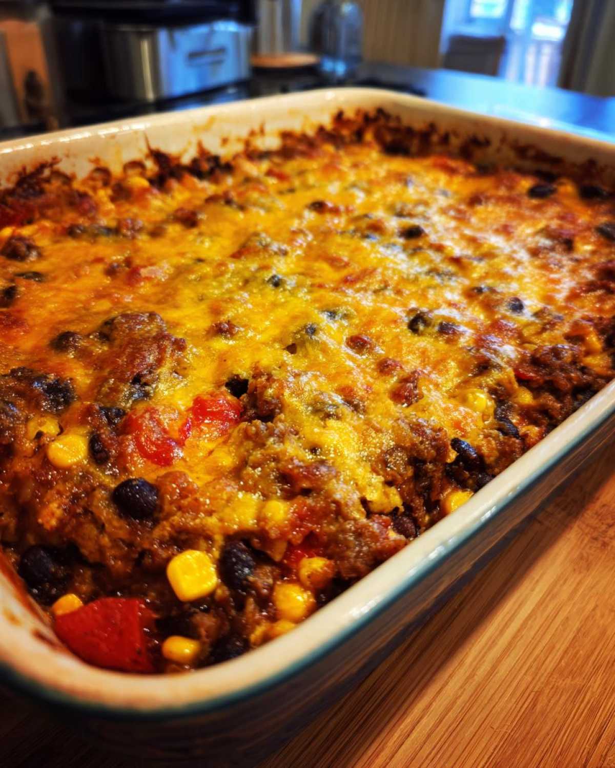 A close-up of a freshly baked Southwestern Black Bean Casserole topped with melted, bubbly cheddar cheese.