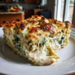 A generous slice of creamy Spinach Artichoke Chicken Casserole with a golden, bubbly cheese top.