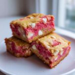 Three stacked squares of rich Strawberry Blondies One Bowl featuring bright pink filling and white chocolate chips.