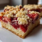 A close-up of a moist square of Strawberry Shortbread Bars Summer Delight with a thick layer of bright red strawberries and a crumbly topping.